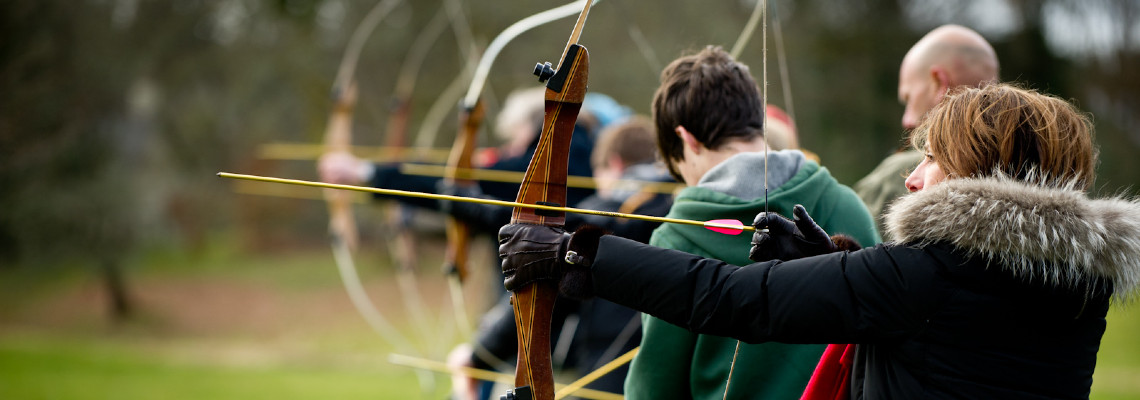 a group of people lining up with archery bows on a cold day - wearing gloves and coats