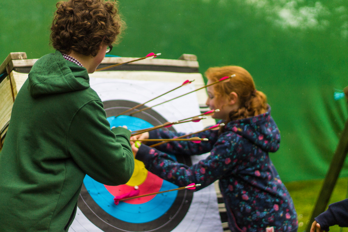 2 young people pulling arrows from an archery target