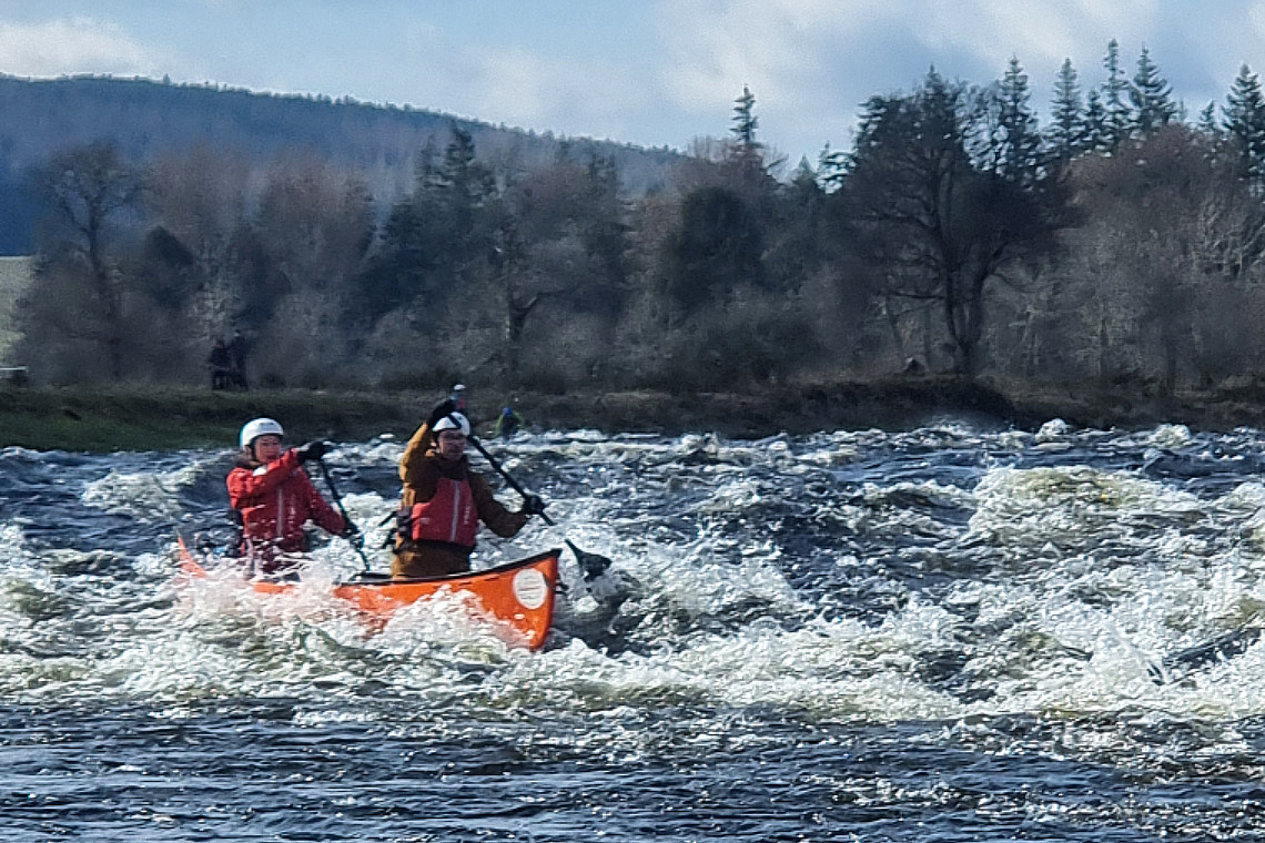 2 people in a canadian canoe, riding the washing-machine rapids on the river spey