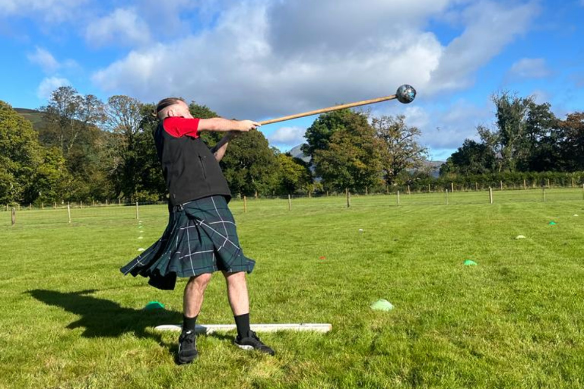 a kilted man throwing a scots hammer during a mini highland games event