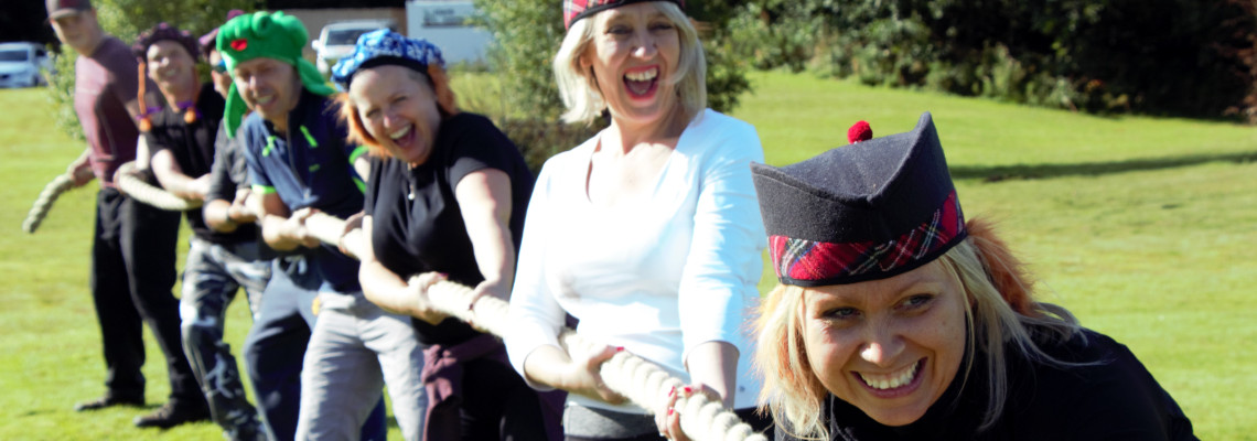 a group of smiling ladies competing in tug of war event in a mini highland games