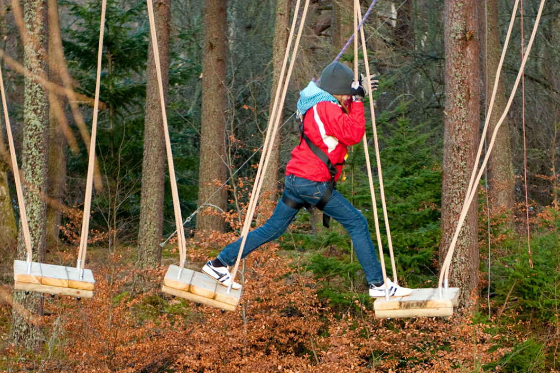 young person stepping across from 1 wobbly suspended platform to another while at treezone treetop adventure course