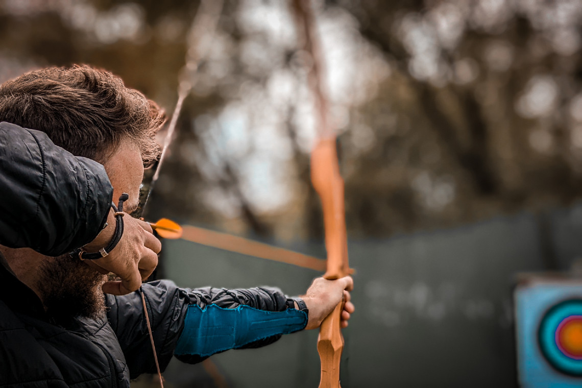 A man holding a bow and arrow and aiming at a target